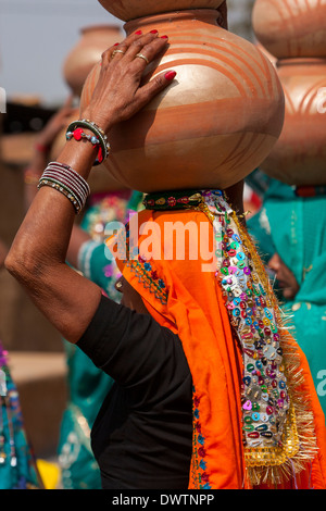 Abhaneri, Rajasthan, India. Donna che cammina con pentole sul suo capo ad una pre-la celebrazione dei matrimoni. Foto Stock