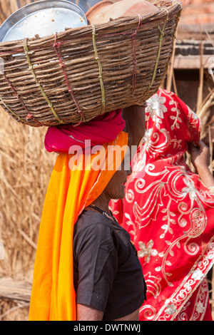Abhaneri, Rajasthan, India. La donna che porta utensili per cucinare o mangiare in un cestello sul suo capo. Foto Stock