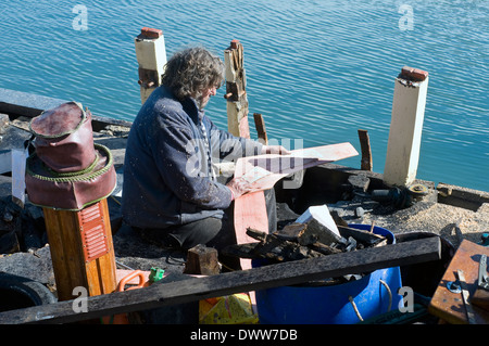 Falegname a carena di nave vecchia brixham devon,barca, godetevi, pesca, fix, felice, hobby, lavoro, manutenzione, l uomo vecchio, vernice, repairin Foto Stock