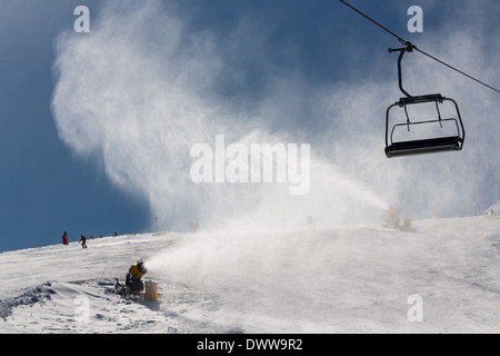 Irrorazione di innevamento artificiale neve sulle piste per sciatori in montagna Foto Stock