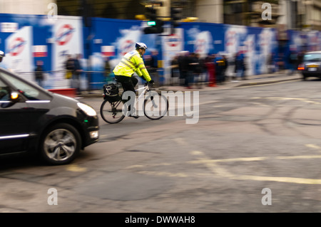 Poliziotto in bicicletta si svolta a destra in Tottenham Court Road proveniente dal New Oxford Street, Londra. Foto Stock