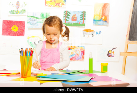 Poco bella ragazza sulle imbarcazioni di lezione di pittura e il taglio della carta a colori Foto Stock