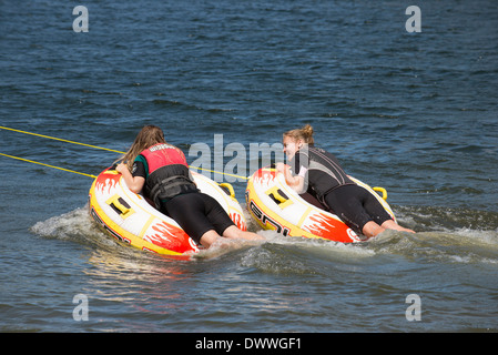 Due ragazze adolescenti ride ciambella gonfiabile trainato da un motoscafo sulle rive di un fiume in Moana Roa Riserva Nord isola NZ Foto Stock