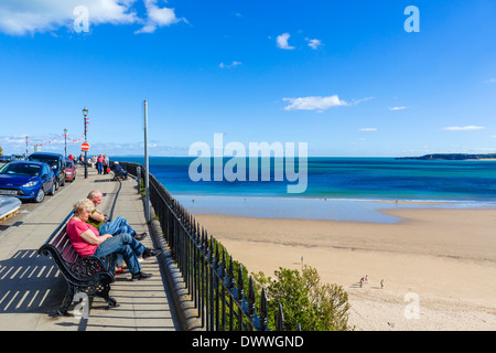 Coppia di anziani seduti su una panchina affacciata sulla spiaggia sulla spianata, Tenby, Carmarthen Bay, Pembrokeshire, Wales, Regno Unito Foto Stock