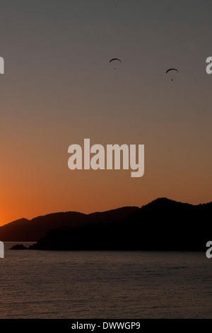 Parapendio oltre le montagne al tramonto in Oludeniz, Turchia Foto Stock