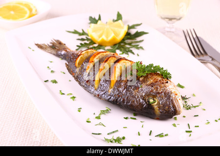 Grigliate di Orate di mare Pesce, limone, la rucola sulla piastra bianca, close up Foto Stock