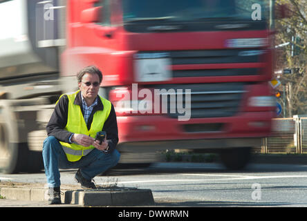 Francoforte sul Meno, Germania. 13 Mar, 2014. Michael Burger sorge sul lato della strada con una basata su GPS dispositivo di rilevamento e un giubbotto di avvertimento in Francoforte sul Meno, Germania, 13 marzo 2014. Egli è un "trassenbegeher' (street walker). Le persone possono utilizzare lo smartphone dispositivo a grandezza di mappa street danni e sporgere denuncia alla polizia. Foto: BORIS ROESSLER/dpa/Alamy Live News Foto Stock