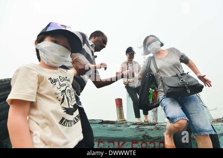 Selangor, Malaysia. Il 14 marzo 2014. I turisti con maschere scendere una barca in Port Klang, Malaysia, Marzo 14, 2014. Le scuole sono chiuse il venerdì a causa dell'aria malsana. L'aria inquinante index (API) di Port Klang, situata ad ovest della capitale Kuala Lumpur, hit livello malsano venerdì, secondo il sito del Dipartimento di Ambiente della Malesia. (Xinhua/Chong Voon Chung) (lmz) Foto Stock