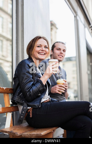 Coppia felice di bere il caffè in tazze monouso sul banco a marciapiede Foto Stock