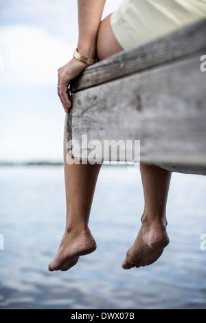 Sezione bassa di donna piedi penzolanti da Pier Foto Stock