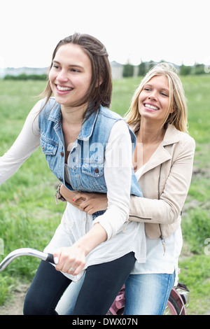 Felice amiche godendo di corsa in bicicletta sulla strada di campagna Foto Stock