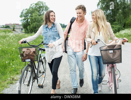 Giovani amici con le biciclette passeggiate sulla strada di campagna Foto Stock