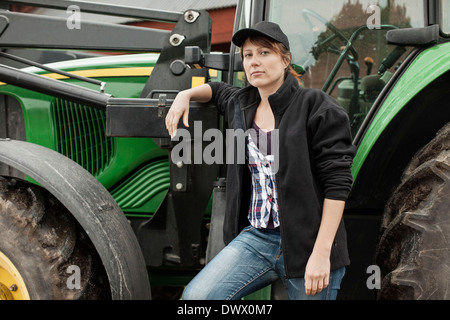 Ritratto di fiducioso agricoltore femmina in piedi dal trattore Foto Stock