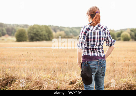 Vista posteriore del contadino femmina permanente al campo Foto Stock