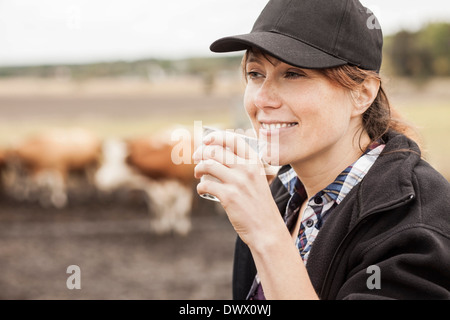 Metà femmina adulta agricoltore bere latte in fattoria Foto Stock
