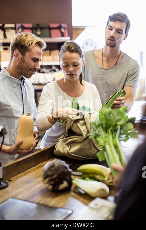 Amici discutendo mentre lo shopping e verdure al supermercato checkout Foto Stock