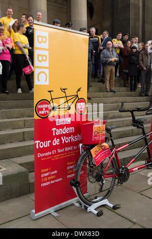 Sostenitori da grandi striscioni, stando in piedi sui gradini di Leeds Town Hall, in attesa di guardare l'inizio di guardare a nord Harry & Amy Tandem del Tour de Yorkshire in aiuto di rilievo dello Sport - West Yorkshire, Inghilterra, Regno Unito. Foto Stock