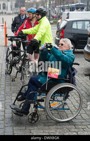 Prima di iniziare guarda a nord Harry & Amy Tandem del Tour de Yorkshire in aiuto di sport di rilievo. Close-up di 4 sostenitori watching (una donna in sedia a rotelle è scattare una foto). Leeds Town Hall, West Yorkshire, Inghilterra, Regno Unito. Foto Stock