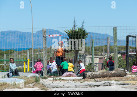 I bambini e il maestro giocando al di fuori di un asilo nido a Khayelitsha, Cape Town, Western Cape, Sud Africa Foto Stock