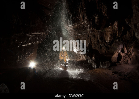 Un speleologo con la cascata nel passaggio di Piccadilly, Ogof Ffynnon Ddu, Galles del Sud Foto Stock