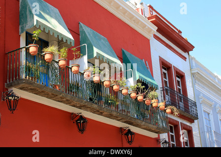 Balcone foderato con vasi di fiori su edificio rosso a Puebla, in Messico Foto Stock