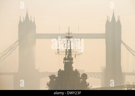 Il Tower Bridge e HMS Belfast visto attraverso la pesante nebbia di mattina e la nebbia in centro a Londra Foto Stock