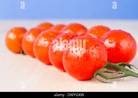 Ciliegia matura pomodori a grappolo su un tavolo con il cielo blu sullo sfondo Foto Stock