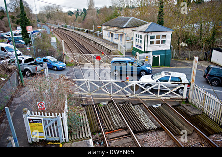 Il traffico su strada che attraversa la linea ferroviaria a East Farleigh stazione ferroviaria con le tradizionali porte e signalbox Foto Stock