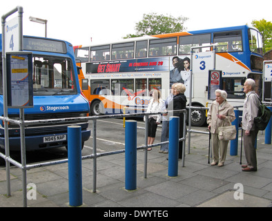 Persone tra cui anziani uomo e donna con bastoni da passeggio queueing & in attesa a Chichester stazione bus Chichester West Sussex Regno Unito Foto Stock