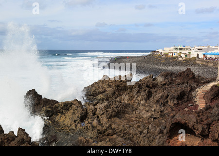 Mare mosso con onde che si infrangono sulle rocce laviche lungo la costa scoscesa al piccolo resort di El Golfo, Lanzarote, Isole Canarie, Spagna Foto Stock