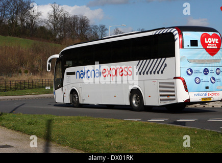 Un autobus National Express viaggia intorno ad una rotonda a Coulsdon, Surrey, Inghilterra Foto Stock