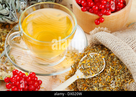 Tazza di tè alle erbe, erbe medicinali e bacche sani sul tavolo Foto Stock