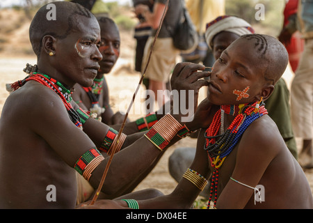 Giovani Hamer uomini dipinto i loro volti a un toro jumping cerimonia nella valle dell'Omo, Etiopia. Foto Stock