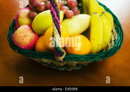 Dono un cesto di frutta riempita con uva, mele, manghi, banane e arance Foto Stock