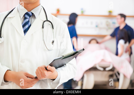 Medico in possesso di una storia medica con finti paziente e la famiglia in ospedale Foto Stock