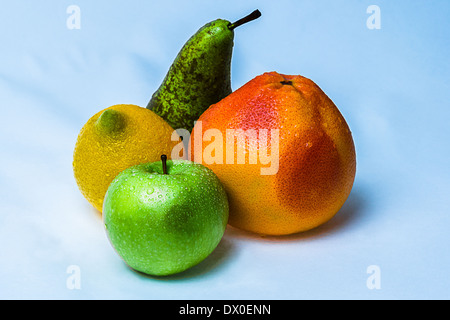Frutti. Vista ingrandita di frutti colorati: arancio pompelmo, mela verde, giallo limone e verde e pera contro sfondo blu Foto Stock