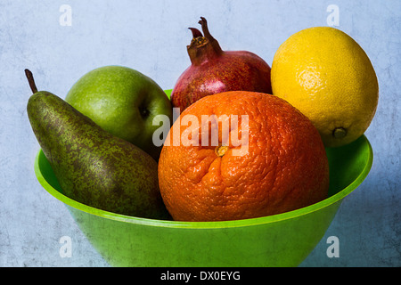 Ciotola di frutti 1. Vista di un verde coppa in plastica con un'arancia, una mela, pera, limone e una melagrana in esso. Testurizzato Foto Stock