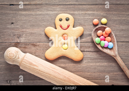 Un singolo gingerbread man su una superficie in legno con la caramella su un cucchiaio e un perno di laminazione Foto Stock