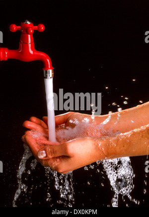 Le mani sotto un rubinetto con acqua corrente Foto Stock