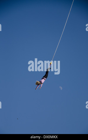 Donna durante bunji salto nel blu del cielo con la luna Foto Stock