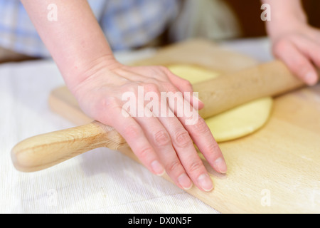 Cucina: donna di stendere la pasta sul tagliere, close-up shot Foto Stock