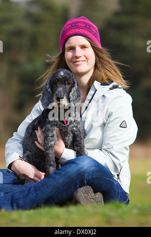 Un vecchio Cocker Spaniel cane seduto fuori su erba in campagna con il suo proprietario Foto Stock