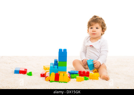 Il Toddler boy giocando con la costruzione di blocchi e seduta sul tappeto di pelliccia home Foto Stock