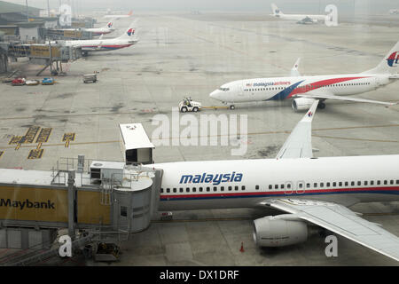 Un Boeing Co. 737-800 aerei operati da Compagnie Aeree malesi System Bhd. (MAS) viene spinto indietro da un cancello come altri aeromobili riposare avvolta nella foschia presso l'Aeroporto Internazionale di Kuala Lumpur (KLIA) a Sepang, in Malesia, Venerdì, 14 marzo 2014 Foto Stock