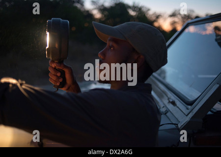 La guida viene fornita con un potente torcia elettrica con guardando gli animali durante il safari notturno Orient Express esegue presso il Camp Foto Stock