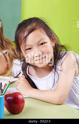 Felice ragazza cinese su un kindergarten sorridente nella fotocamera Foto Stock