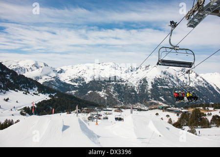 Impianti di risalita a Soldeu Andorra, stazione di sport invernali. Gli sciatori seduti su una sedia lift passando sopra la slope style free ski area di Soldeu in sun. Foto Stock