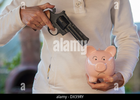 Cina rosa salvadanaio minacciato con una pistola Foto Stock