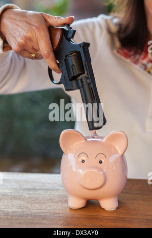 Cina rosa salvadanaio minacciato con una pistola Foto Stock