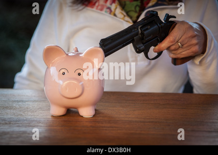 Cina rosa salvadanaio minacciato con una pistola Foto Stock